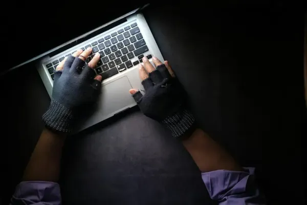 Assicurazione Cyber - mani con guanti senza dita su notebook
